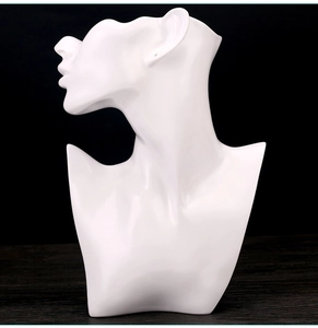 Macro shot of white resin mannequin bust jewelry stand on a dark wooden table