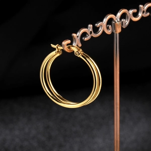 Detail of triple-layer gold titanium steel hoop earrings on a vintage display stand