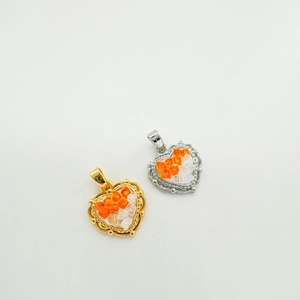 Close-up of heart-shaped 18K gold-plated pendants with orange and clear zircon crystals