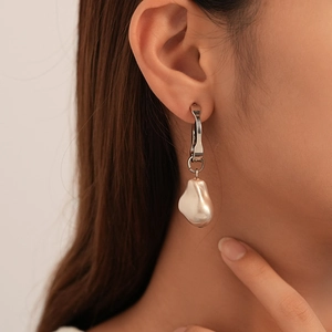 Gros plan d'une boucle d'oreille élégante en perle baroque irrégulière portée