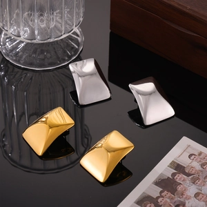 Minimalist 18K gold and silver geometric rectangular stud earrings on reflective surface