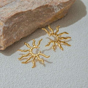Detailed shot of vintage 18k gold plated sun earrings on a natural stone background