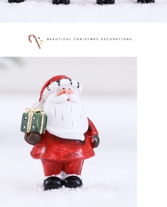 Close-up of resin Santa Claus figurine with a green gift box on a snowy background