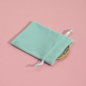 Close-up of a mint green plush drawstring jewelry pouch with a gold bracelet detail