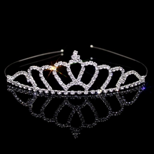 Macro shot of silver metal crown headband with sparkling rhinestones on black reflection