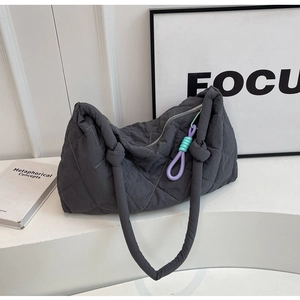 Detail of dark grey quilted shoulder bag featuring a purple and mint green knotted charm