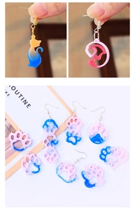 Detail of pink and blue resin cat paw earrings and moon kitty pendant charms