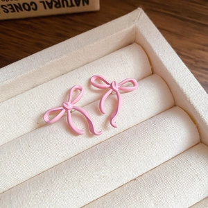 Macro detail of sweet pink bowknot stud earrings on soft velvet jewelry tray