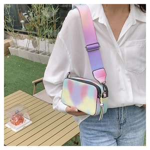 Detail of gradient rainbow camera bag featuring wide strap and metal hardware on model