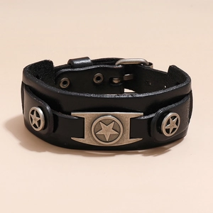 Dettaglio del bracciale in pelle nera con stelle d'argento vintage su sfondo beige