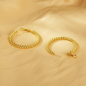Detail showing the golden twisted rope texture on elegant stainless steel hoop earrings