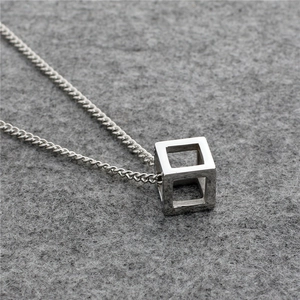 Macro view of silver geometric hollow cube pendant on curb chain with 316L steel texture