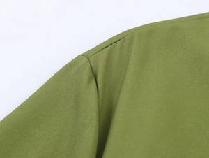 Close-up of precise stitching and seam detail on green woven dress shoulder area