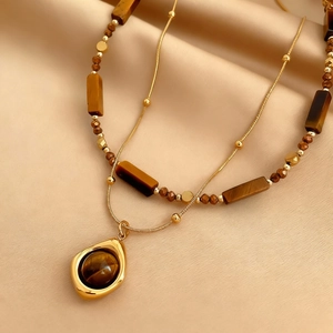 Vintage gold layered necklace with tiger eye beads on champagne silk background