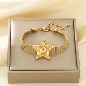 Detail of gold mesh band bracelet featuring a large 3D star pendant on a jewelry box