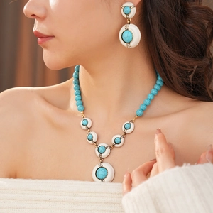 Detail of vintage turquoise resin bead necklace and stud earrings set on a female model