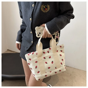 Detail of corduroy tote bag with red strawberry pattern showing texture and handle