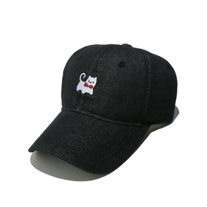 Detailed close-up of cute white cat embroidery on a black denim baseball cap fabric