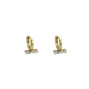 Détail de boucles d'oreilles créoles dorées géométriques avec perles et strass brillant