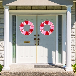Couronnes de cœur de Saint-Valentin en feutre rouge, rose et blanc sur une porte blanche