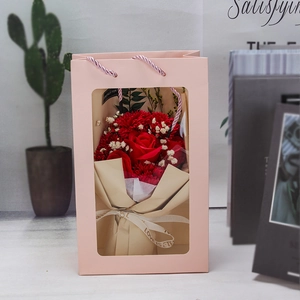 Pink gift bag with transparent window showing a bouquet of soap roses and carnations