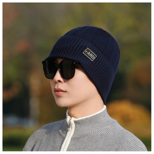 Detail of dark blue ribbed knit beanie featuring IFARDI brand patch with model