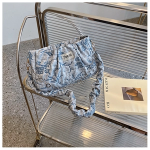 Detailed shot of blue ruched texture handbag with silver chain on a metallic trolley