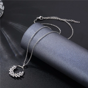 Macro detail of silver leaf zircon necklace featuring a round olive branch pendant design