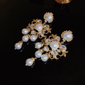 Detail of vintage gold earrings with pearls and crystals on reflective black backdrop