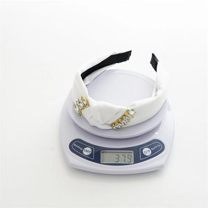 Detailed view of knotted white fabric headband with sparkling rhinestones weighing 37.9g