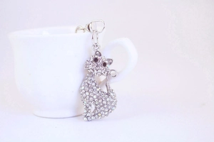 Macro detail of silver alloy cat keychain with sparkling rhinestones on white background