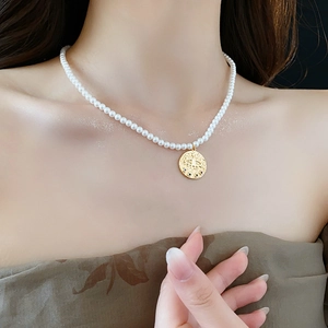 Vue détaillée d'un pendentif pièce œil plaqué or avec perles sur un collier vintage