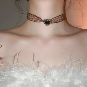 Macro detail of brown lace choker necklace with pearl-rimmed black heart pendant