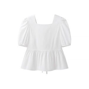 Détail de la blouse blanche à manches bouffantes avec ourlet volanté et tissu lisse