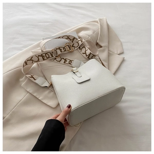 Detail of white lychee leather bucket bag with jacquard geometric wide strap and gold hardware