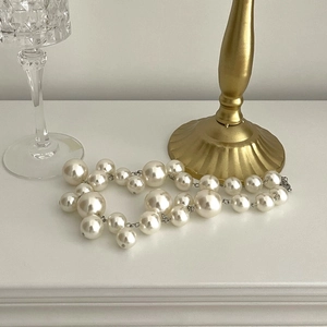 Elegant beaded pearl grape necklace with layered white pearls on a white surface