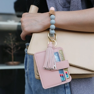 Macro detail of a pink leather card holder with tassel and beaded silicone wristlet