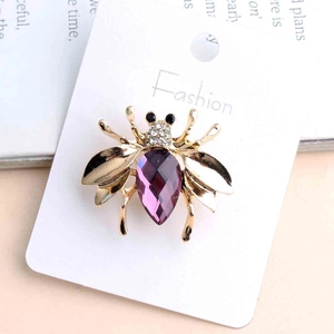 Detailed view of bee brooch with purple drop crystal and white rhinestones