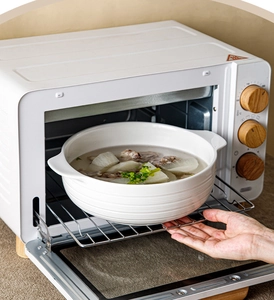 White ceramic soup bowl with handles and ribbed design shown inside a modern oven