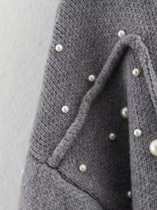 Detailed view of grey knitted fabric texture adorned with elegant white pearl accents