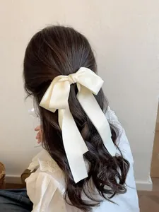 Détail d'une pince à cheveux avec nœud en satin blanc crème et de longs rubans fluides