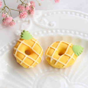 Makroaufnahme von zwei gelben Ananas-Donut-Anhängern aus Harz für DIY-Haarschmuck
