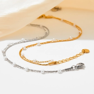 Detailed view of layered gold and silver pearl necklaces on soft beige silk background
