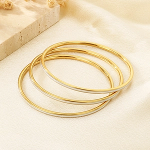 Detailed macro view of three stackable gold bangles with white enamel inlay accents