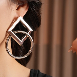 Gros plan de boucles d'oreilles géométriques en argent avec formes carrées et circulaires