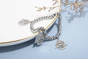 Detailed macro view of silver beaded bracelet featuring a polished Hamsa Hand charm