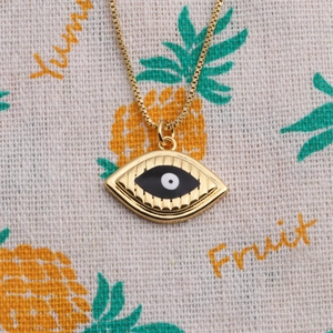 Close-up of gold-plated evil eye pendant with black and white enamel on a thin chain