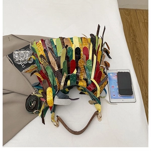 Detailed view of colorful patchwork fringe handbag with boho tassels and woven shoulder strap