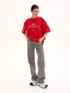 Detail of red cotton t-shirt with white text print paired with grey straight jeans