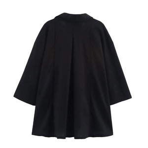Detail of loose black linen blouse with V-neckline and textured woven fabric surface